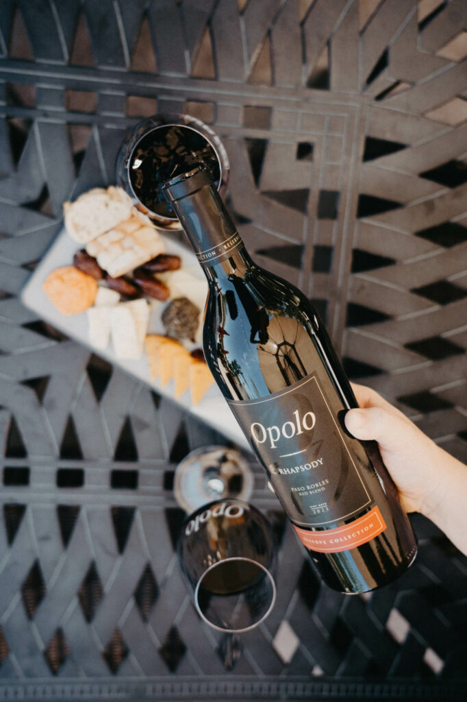 Overhead view of a bottle of Opolo Cabernet Sauvignon being poured into a glass with a cheese plate