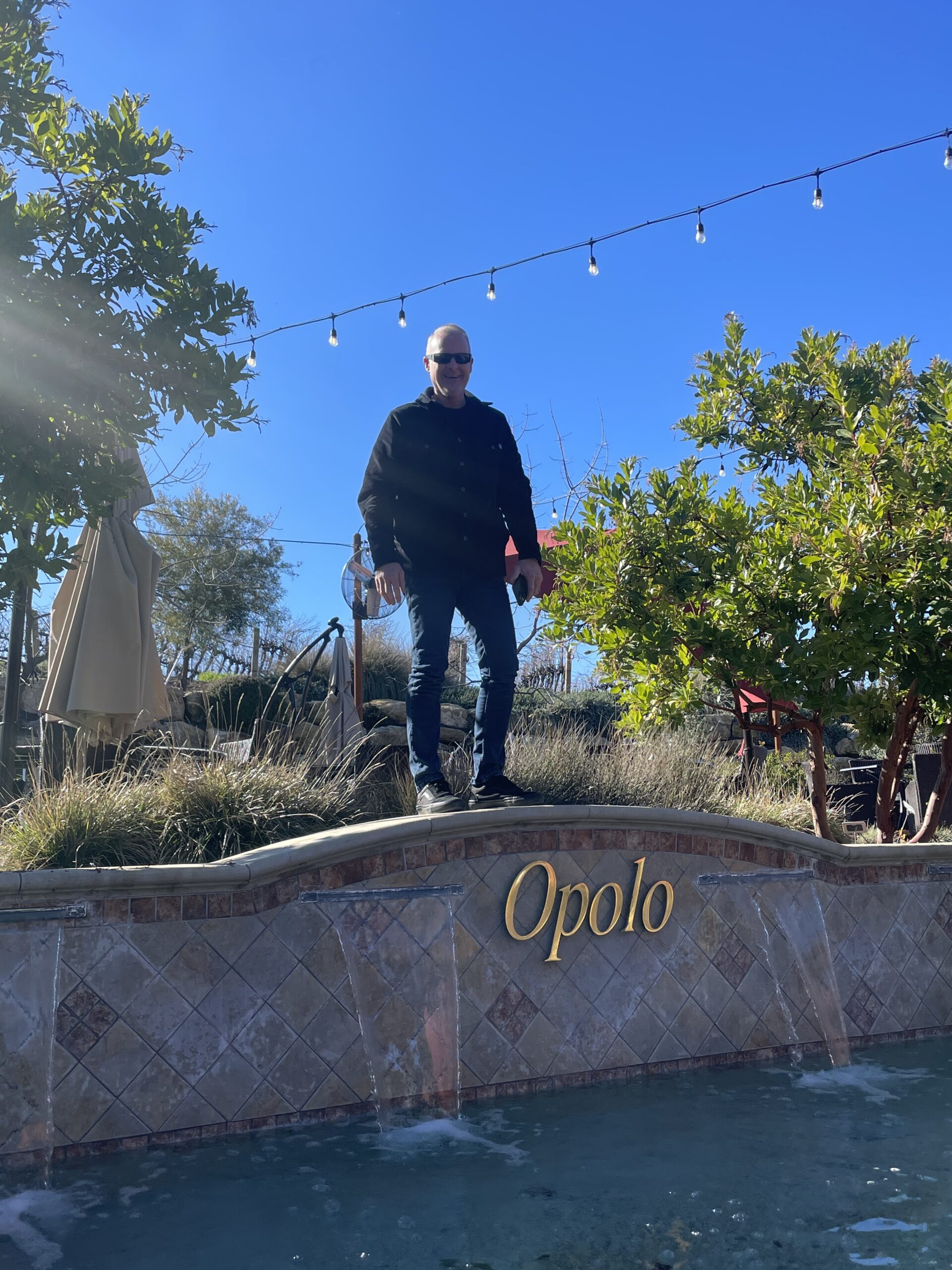 Man standing on a wall above the Opolo logo