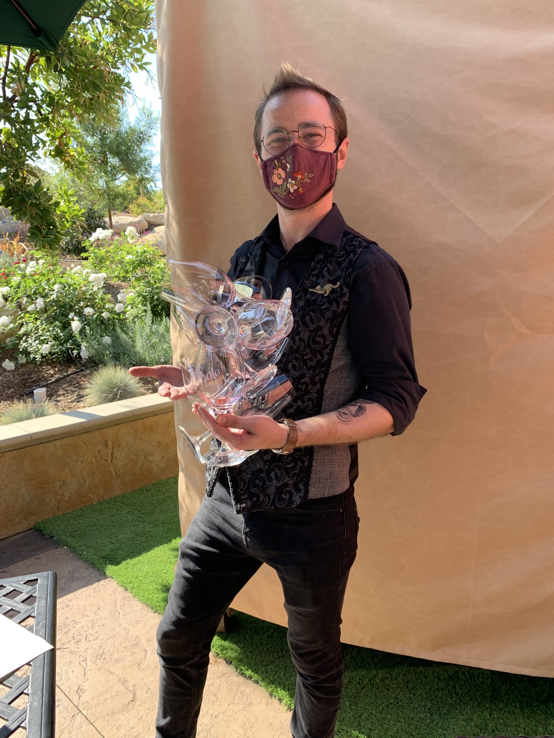 Opolo Vineyard employee in a mask holding a large amount of empty wine glasses